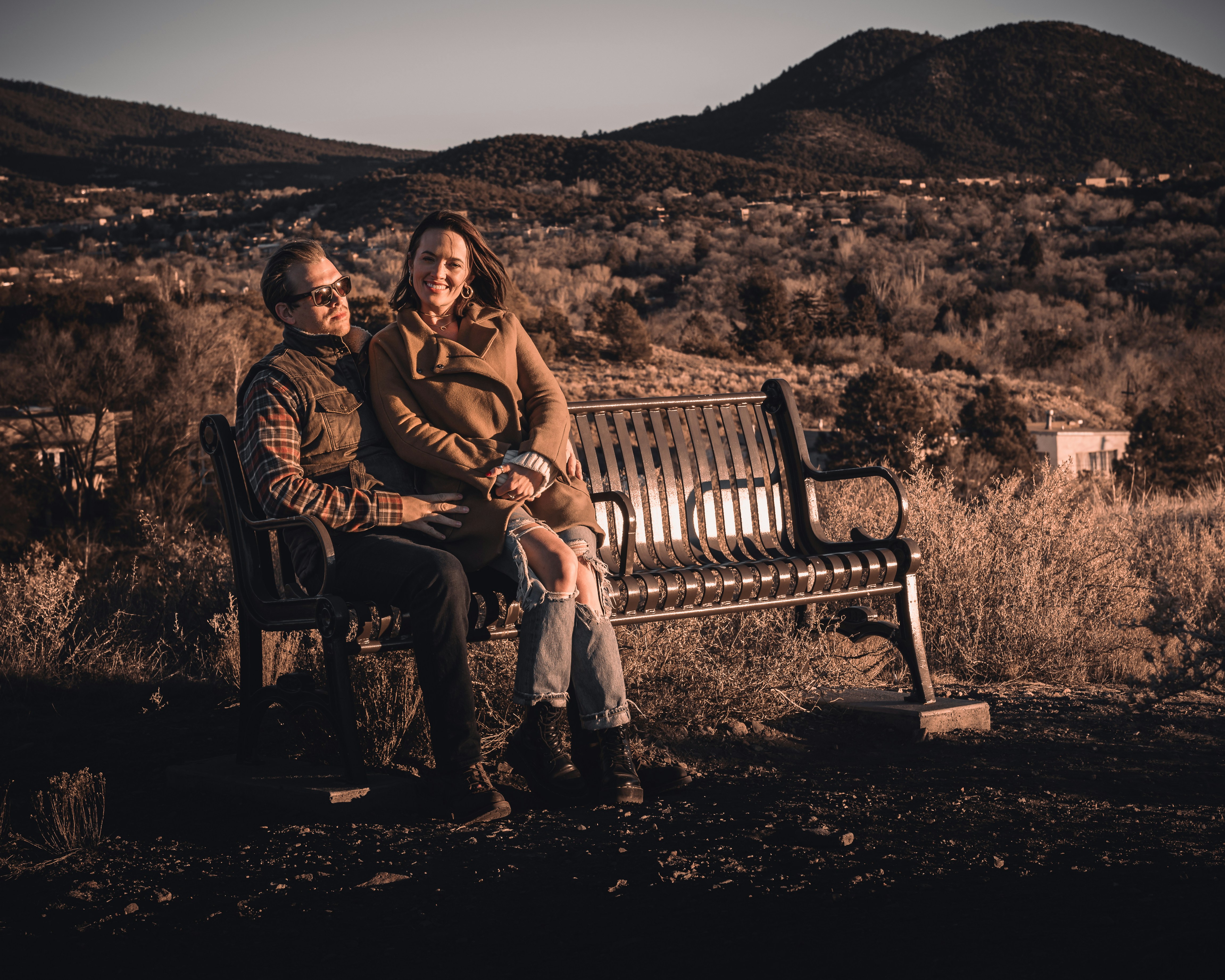 man and woman sitting on brown wooden bench