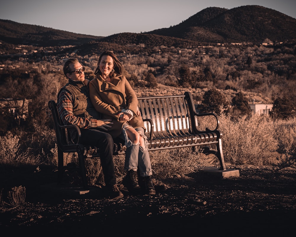 man and woman sitting on brown wooden bench