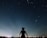 A serene person looking thoughtfully at a starry night sky.