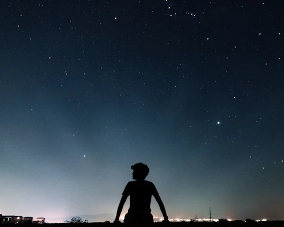 A father and daughter sitting side by side, watching the stars in the night sky.