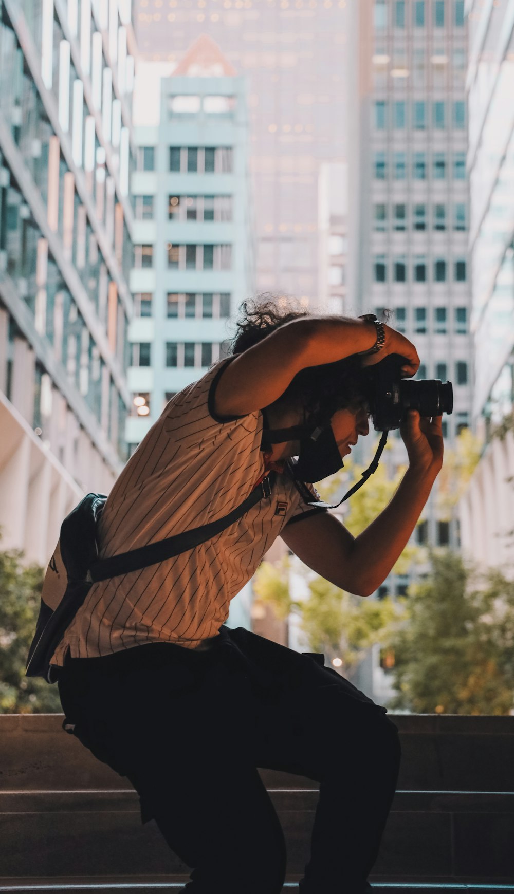 Mann in braunem T-Shirt und schwarzer Hose mit schwarzer DSLR-Kamera