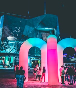 people standing near pink lighted building during night time