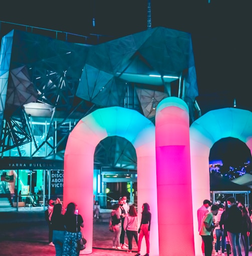 people standing near pink lighted building during night time