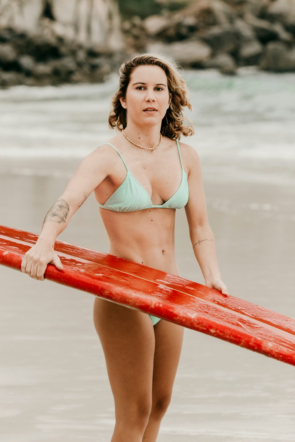 woman in white bikini standing on red surfboard
