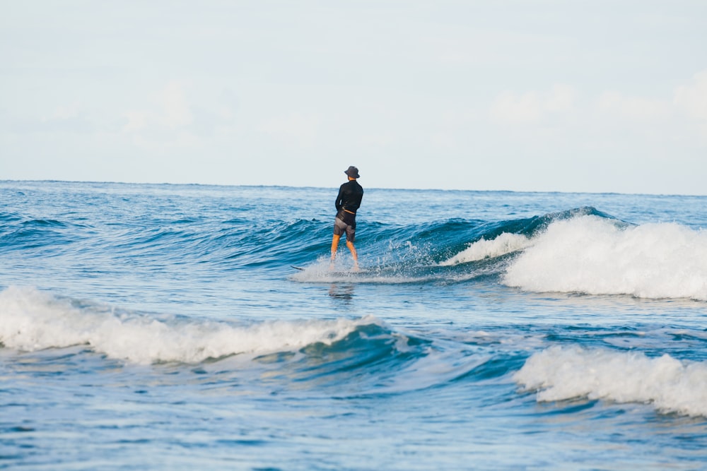 man in black shorts surfing on sea waves during daytime