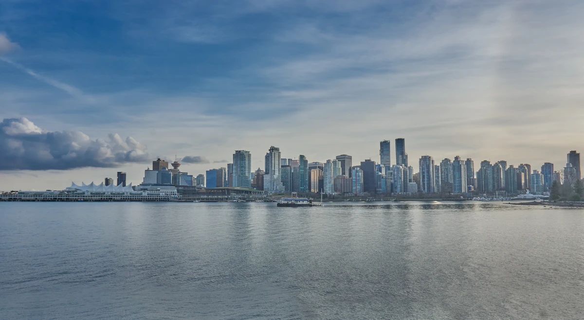 The downtown Vancouver skyline seen across the water from the seawall with the high-rise towers reflected in the calm inlet