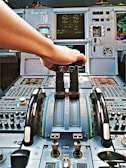 Close-up of a pilot's hand adjusting flight controls inside the cockpit.