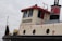 A close-up view of the upper part of a tugboat with a sign labeled 'BARNHOUSE'. The structure features a cream-colored exterior with red and black accents. There is a large window on the side, a ladder, and round portholes.