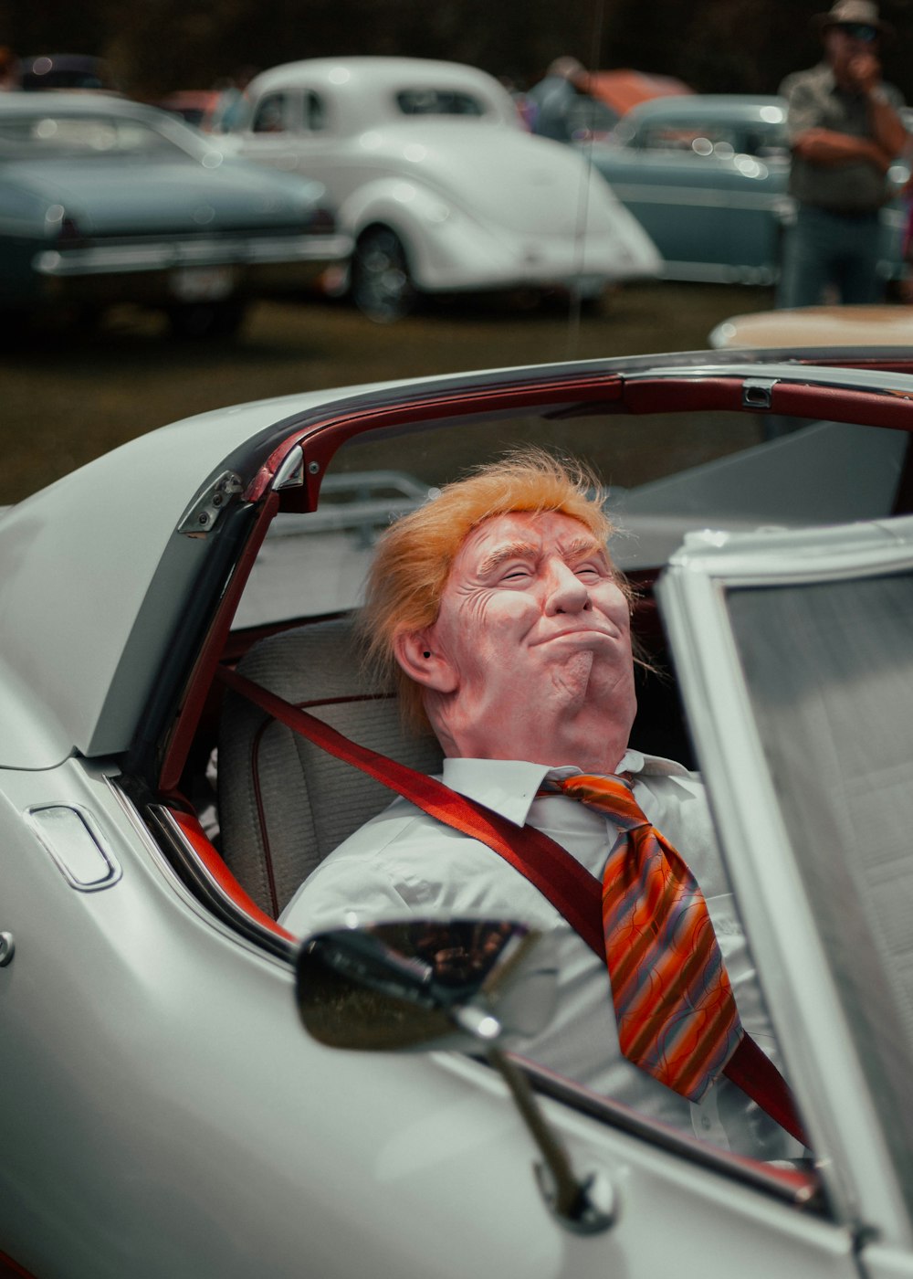 man in red white and black striped necktie sitting on car seat