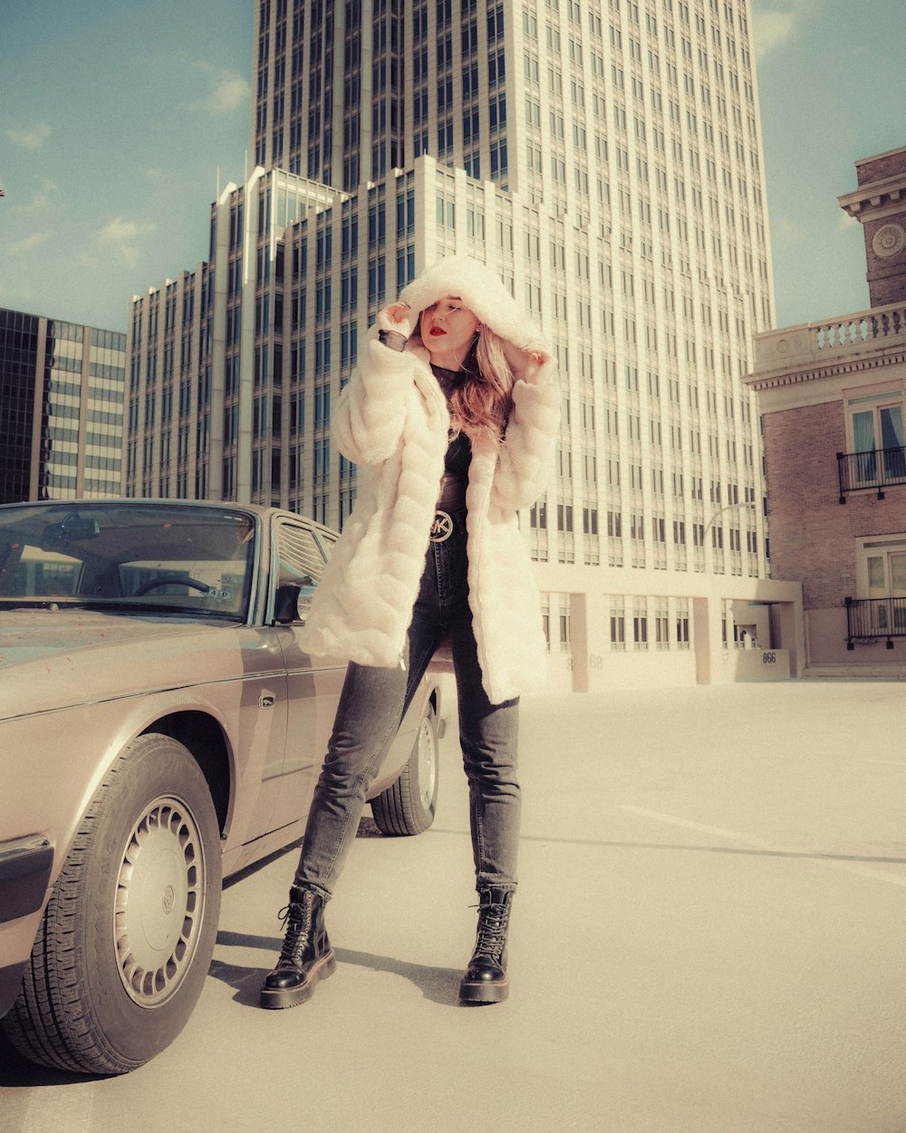 woman in white coat standing beside black car during daytime