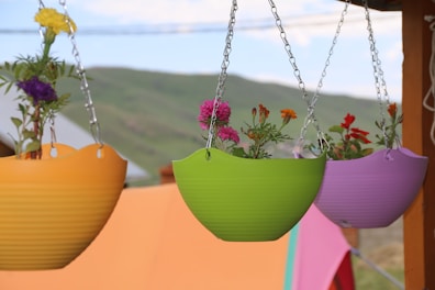 A cluster of hanging planters with vibrant faux trailing vines and colorful pots.