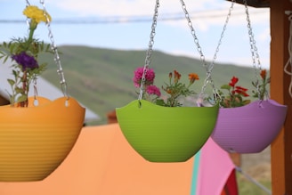 A cluster of hanging planters with vibrant faux trailing vines and colorful pots.