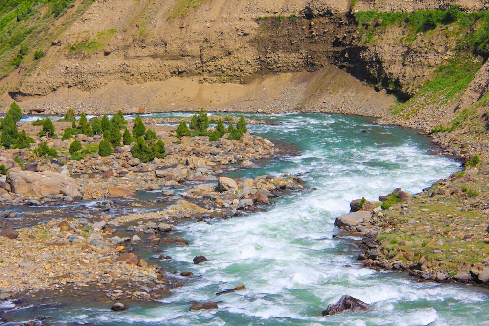 brown rocky mountain beside river during daytime