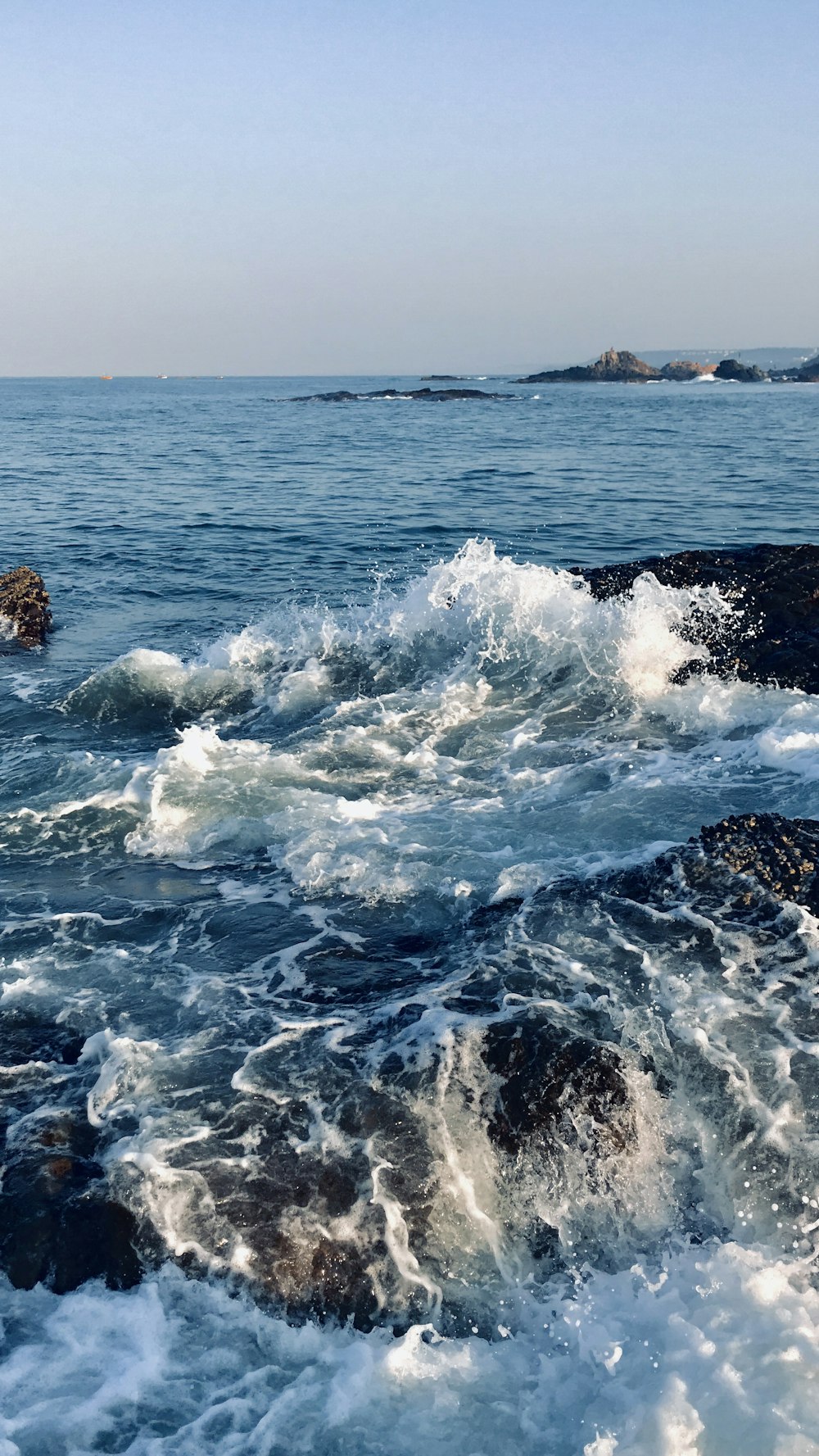 ondas do oceano batendo em formação rochosa marrom durante o dia