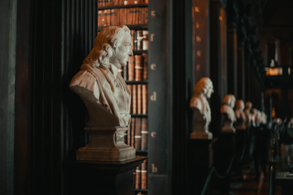 White marble bust on black pedestal dominates library scene amidst towering bookshelves