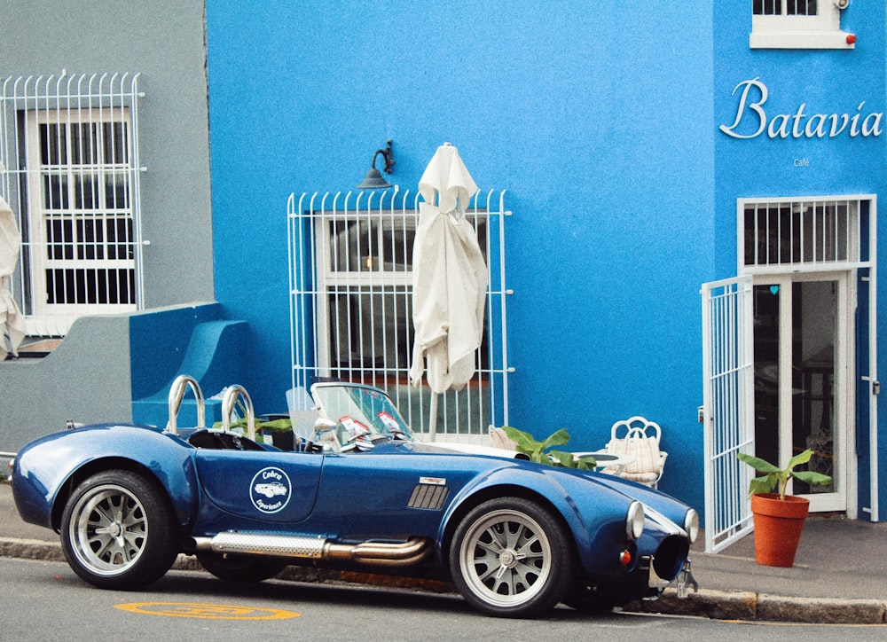 black convertible car parked beside white metal gate during daytime