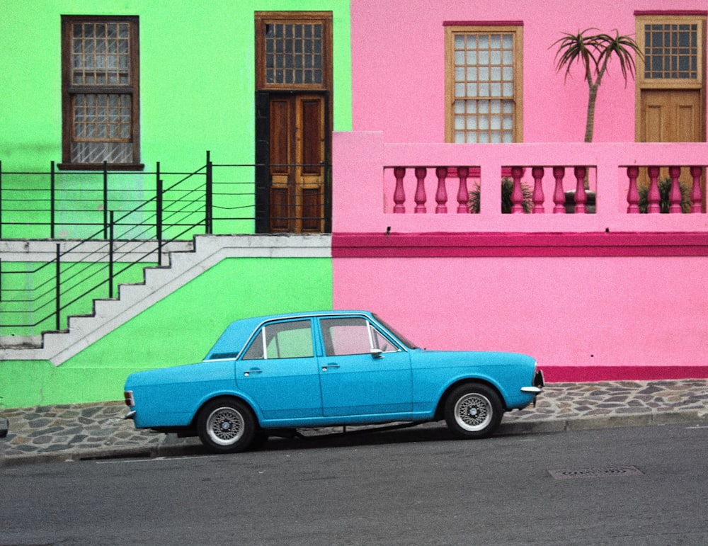 blue car parked beside pink concrete building during daytime