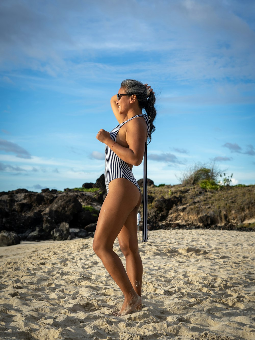 femme en bikini à rayures blanches et noires debout sur la plage pendant la journée