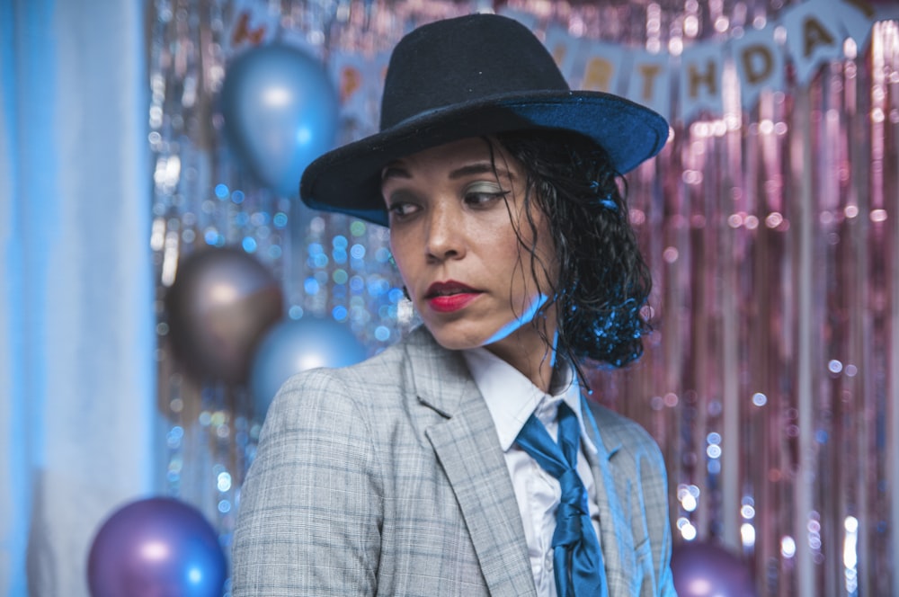 woman in gray and black plaid blazer wearing black hat