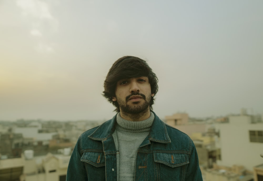 man in blue denim jacket standing on field during daytime