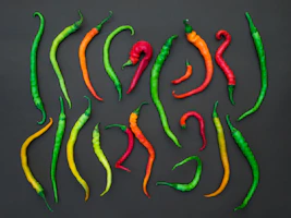 Fresh green chilies and aromatic spices arranged artistically on a dark background