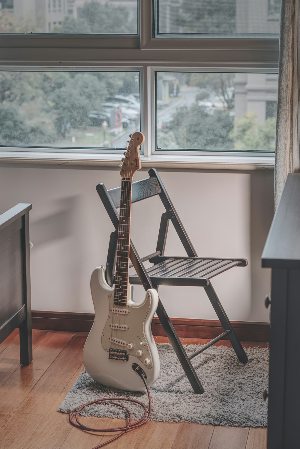 white and brown stratocaster electric guitar on black metal stand