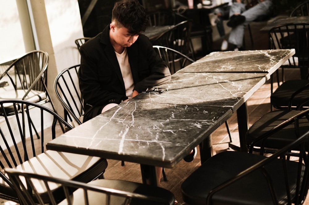 man in black suit jacket sitting on black chair