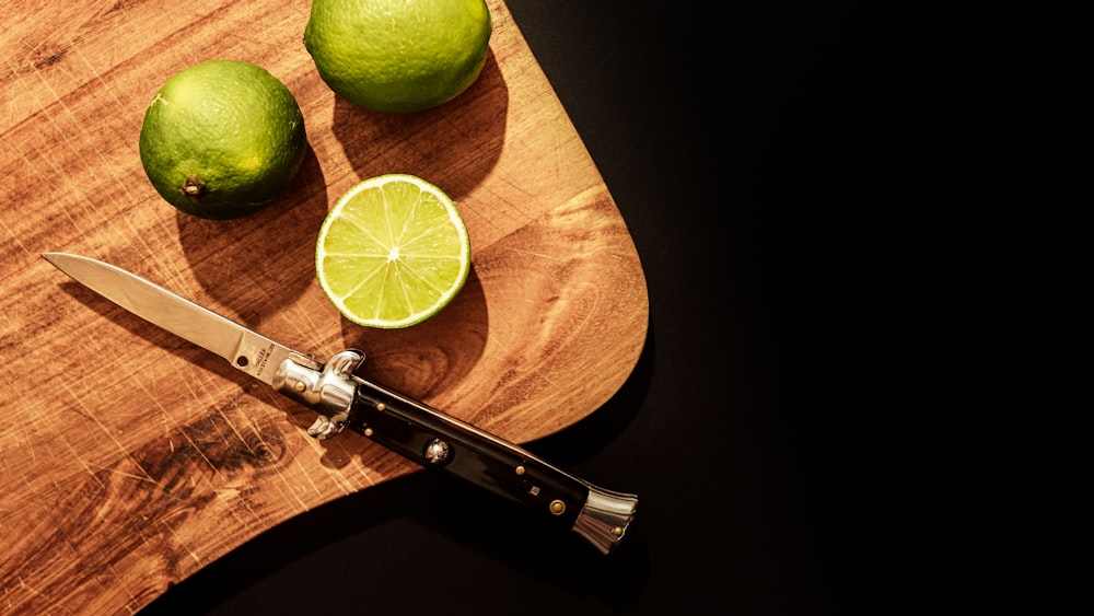 sliced lemon beside black handle knife on brown wooden table