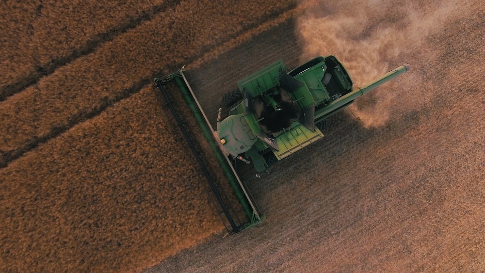 a green tractor is driving through a field