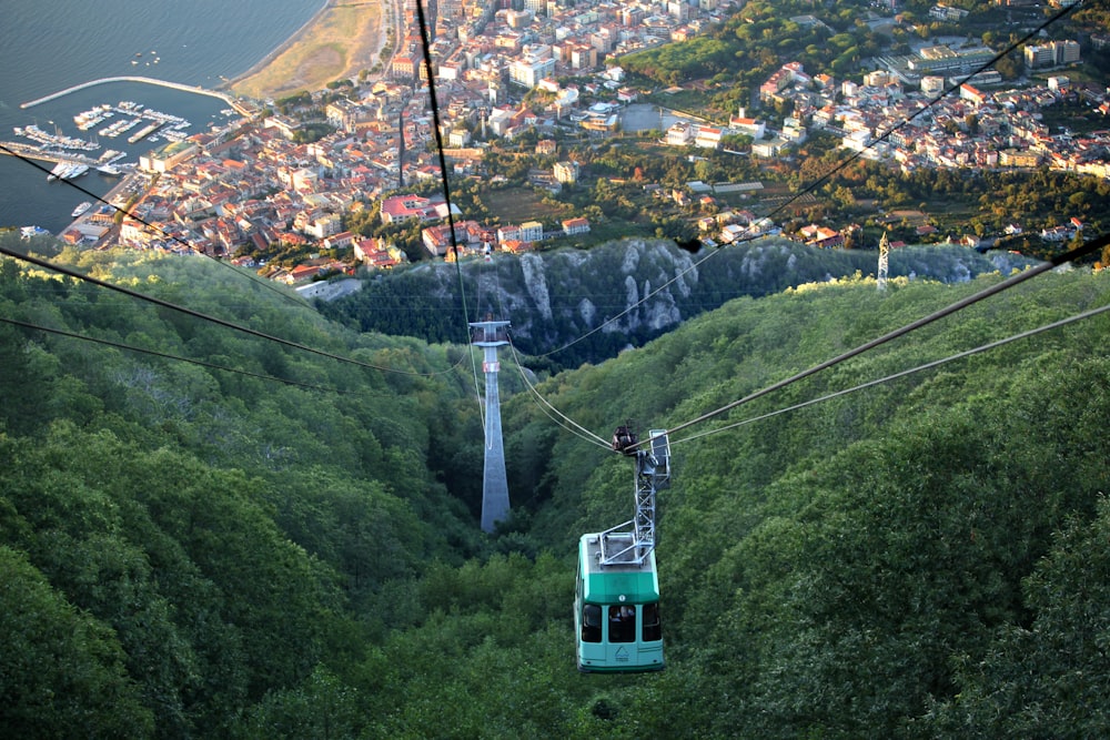 green cable car over green trees and houses during daytime
