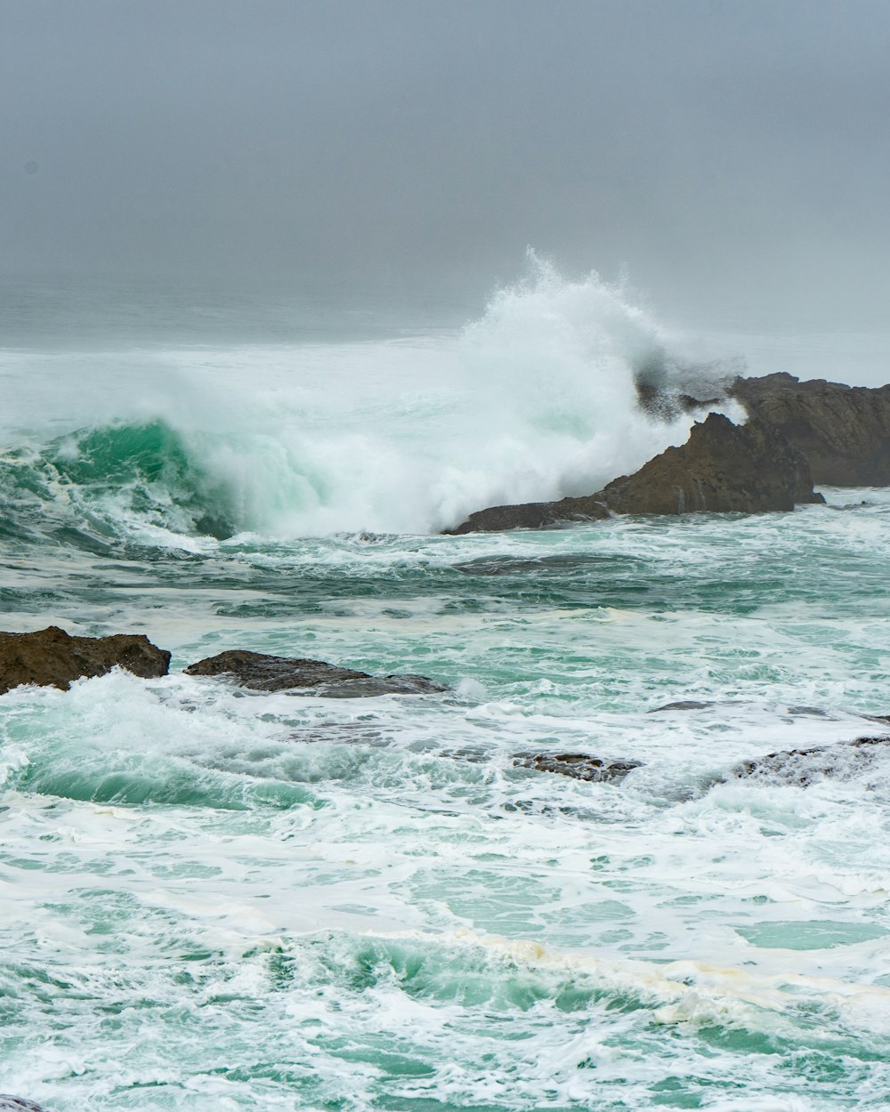 ocean waves crashing on brown rock formation during daytime