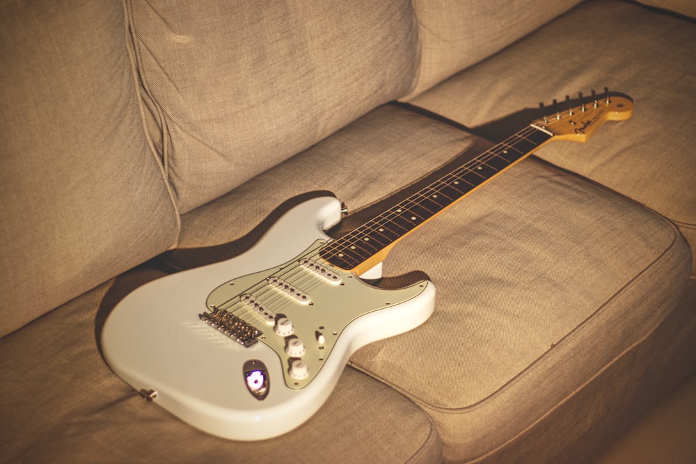 Guitare électrique Stratocaster blanche et noire sur canapé marron