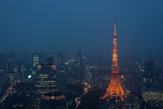 A stunning high-rise tower glowing at dusk with city lights below.