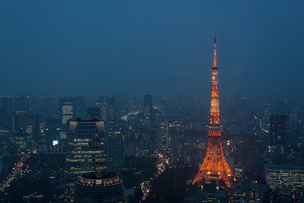Tokyo Tower glowing orange above the dark blue cityscape of Minato City, Japan