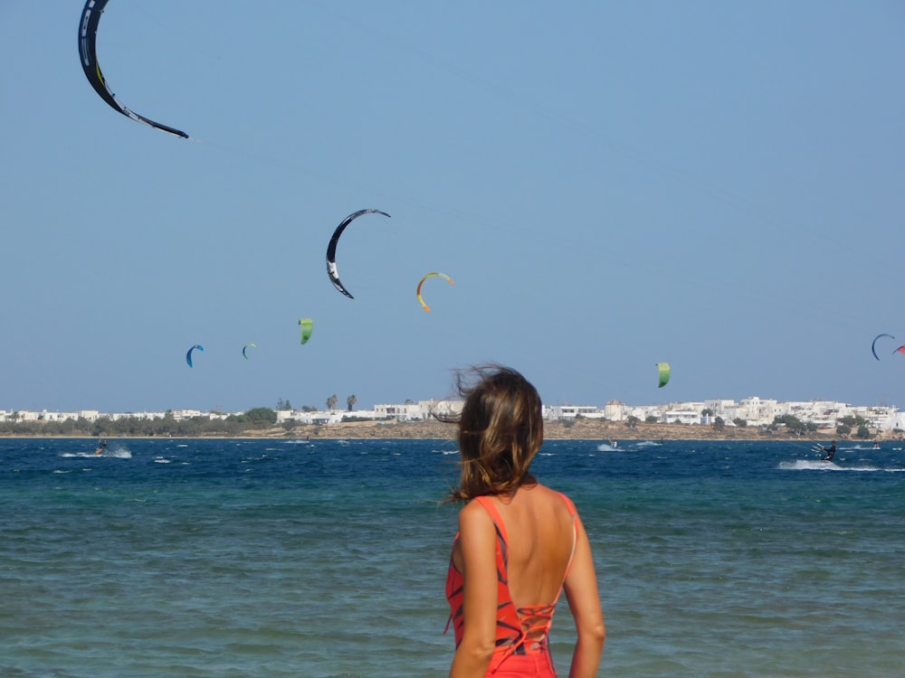 woman in orange bikini top holding black bird flying over the sea during daytime