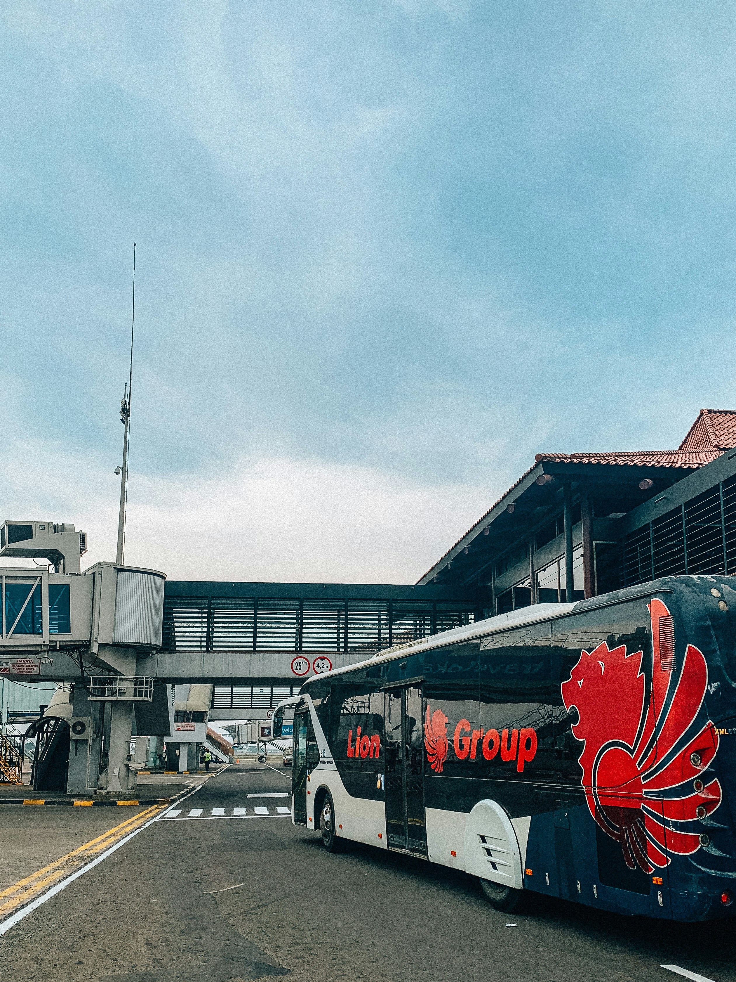 Charter bus parked at airport terminal pickup zone, passengers boarding with luggage