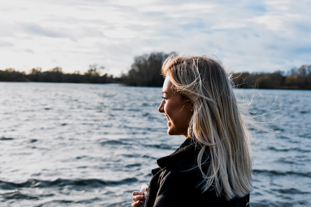 woman in black jacket standing near body of water during daytime