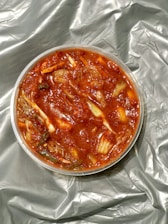 Close-up of a rustic jar filled with bubbling homemade kimchi on a wooden table.