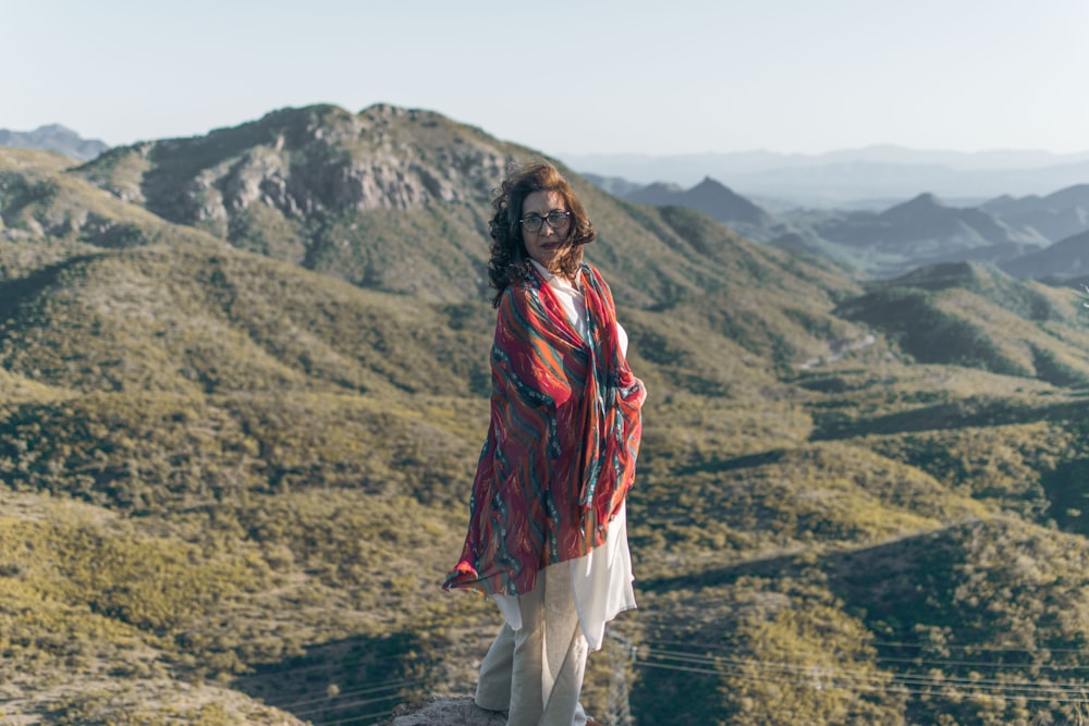 woman in red and black scarf standing on green grass field during daytime