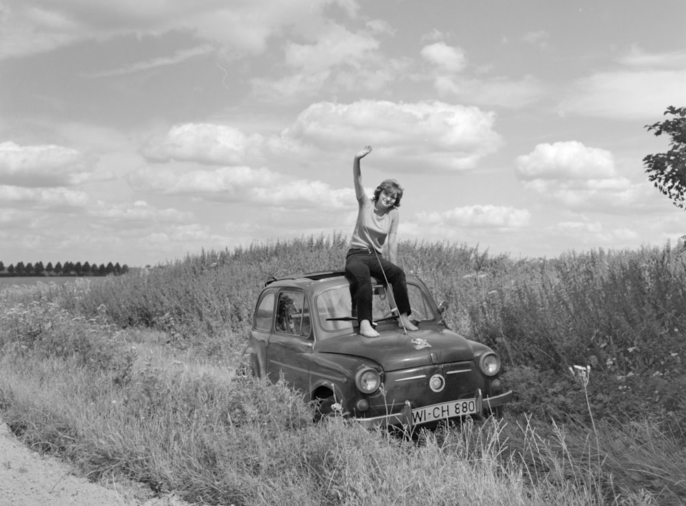 woman in black dress sitting on black car