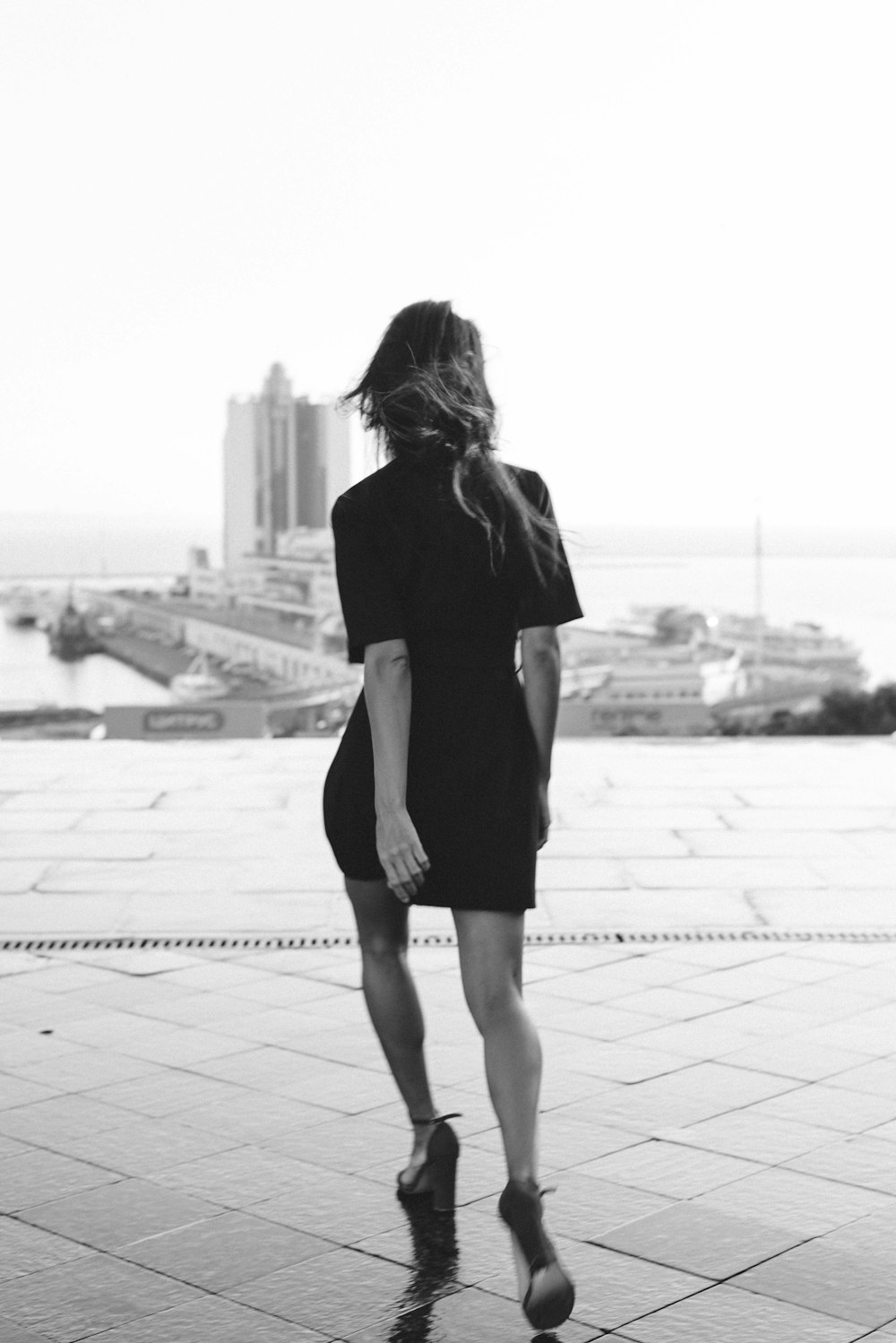 Frau in schwarzem Kleid, die tagsüber auf dem Bürgersteig spazieren geht