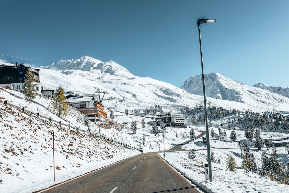 brown and white house near mountain covered with snow under blue sky during daytime