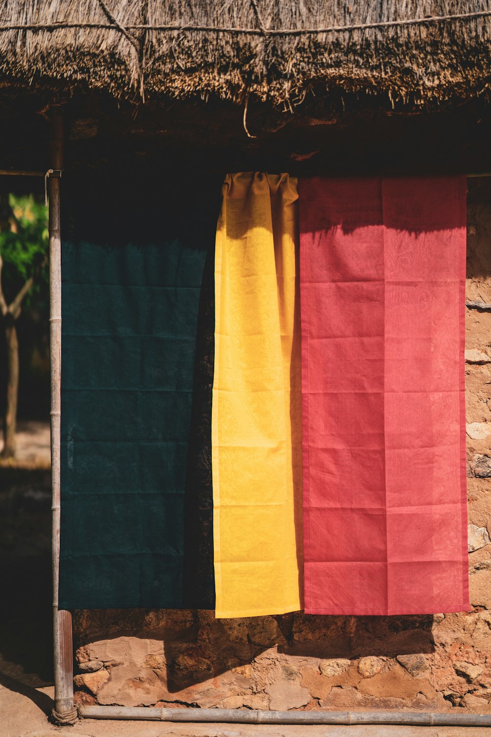 yellow and pink textiles hanged on brown wooden pole