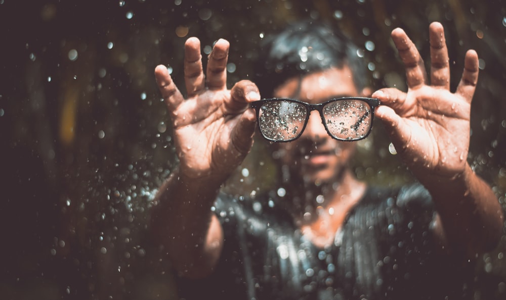 person holding black framed sunglasses