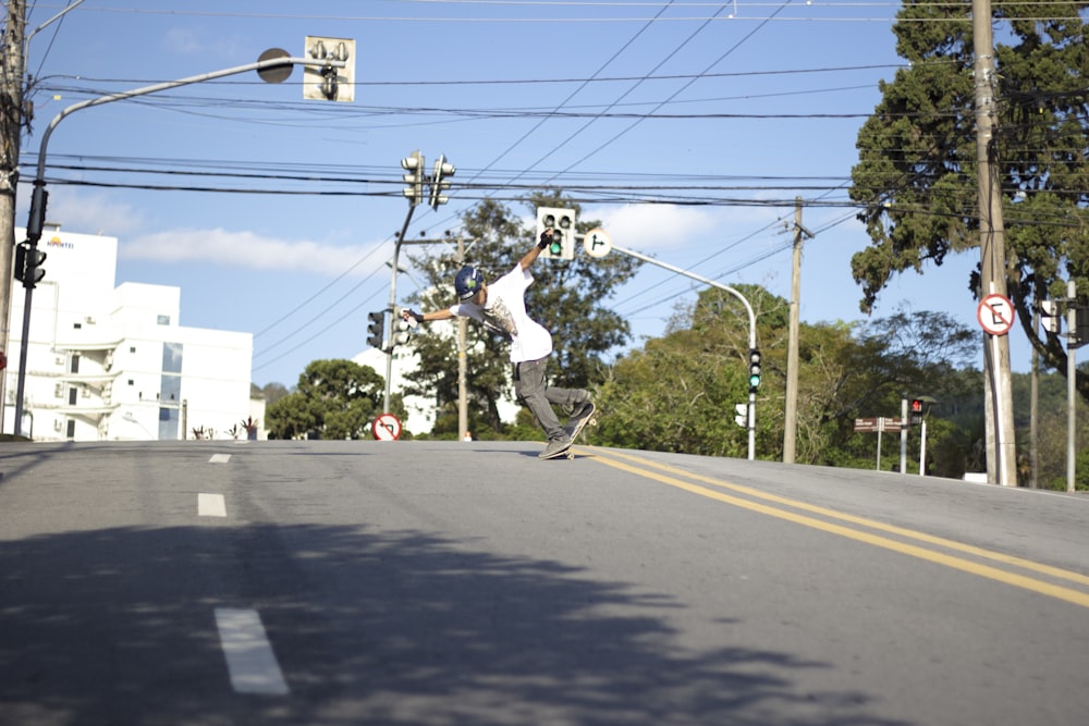 man in white shirt and black pants riding on black skateboard during daytime