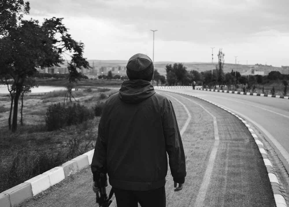 man in black hoodie standing on road