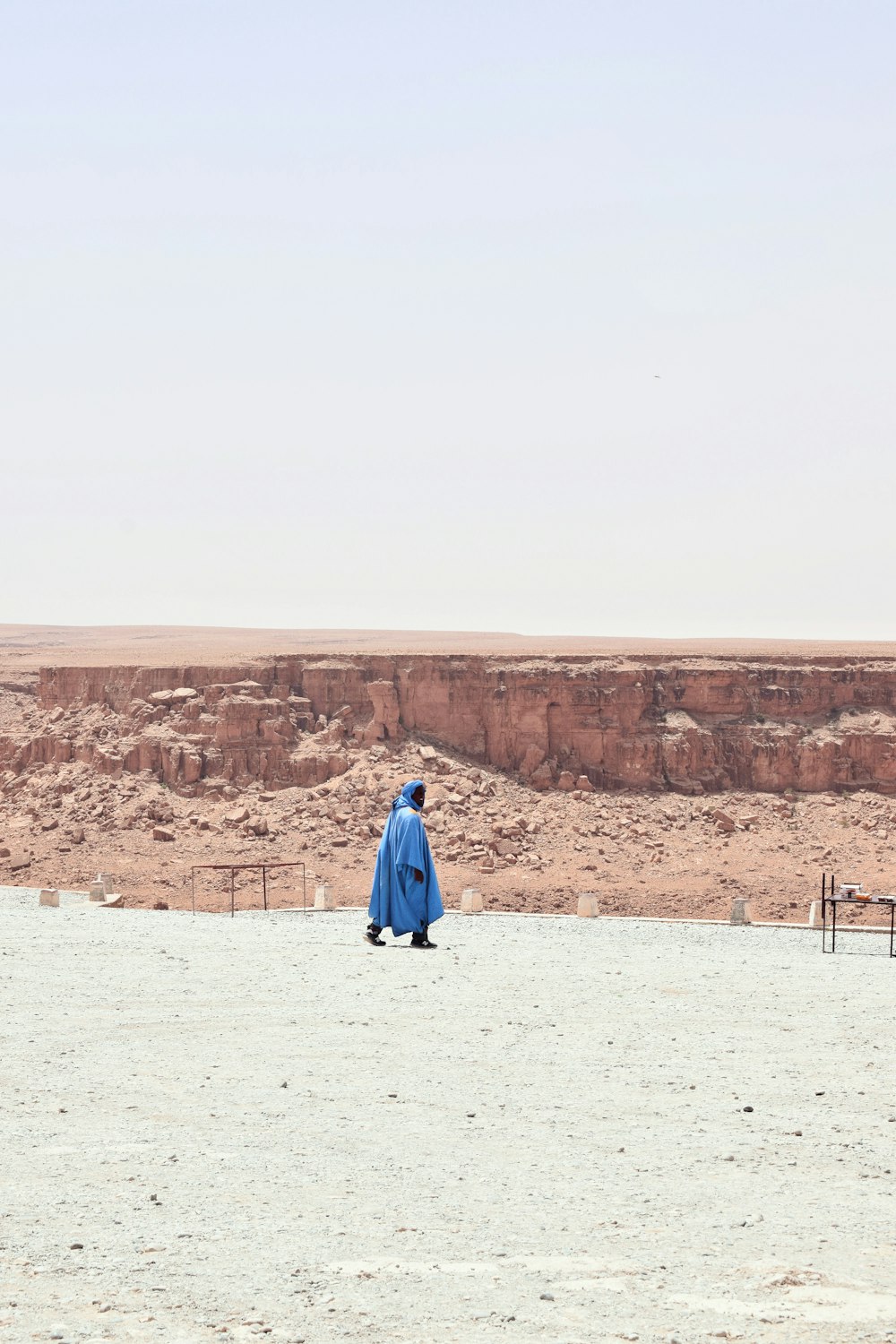 Frau im blauen Kleid geht tagsüber auf weißem Sand spazieren