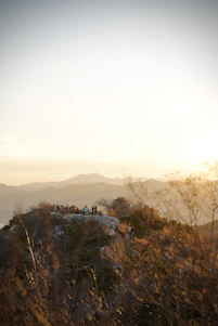 A group of happy adventurers sharing a joyful moment atop a scenic mountain peak at sunset.