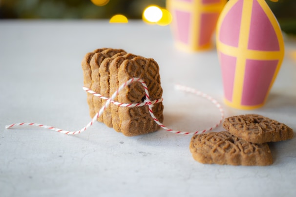 Stack of golden brown butter cookies tied with a red ribbon on a kitchen counter.