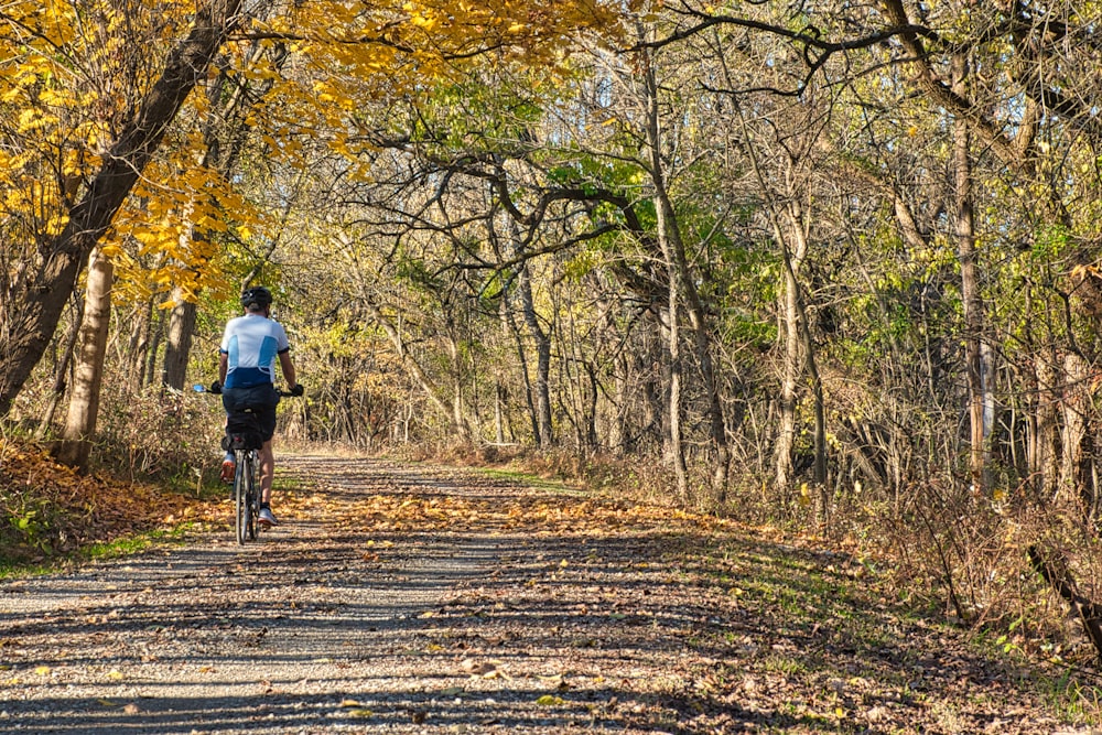 man in blue shirt riding bicycle on road during daytime